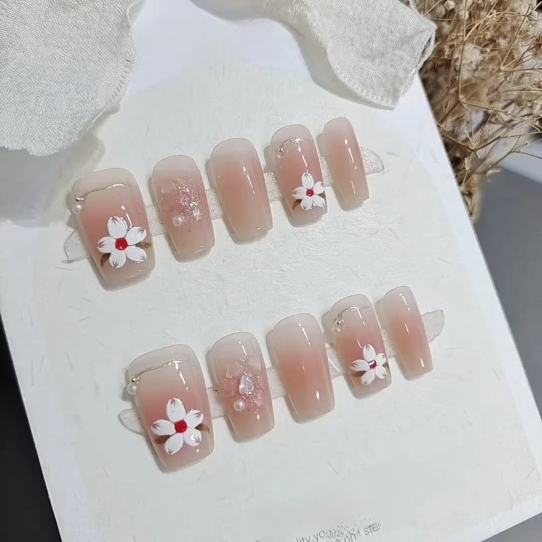 Krótkie paznokcie naklejane w kształcie trumny, różowy odcień blush, wzór magnolii