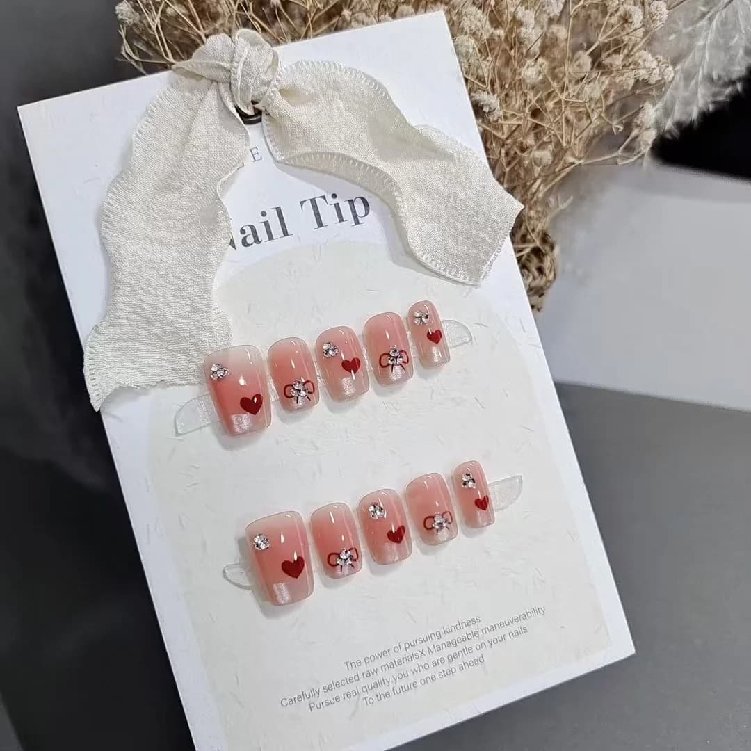 Krótkie kwadratowe tipsy naklejane z francuskim manicure, sercami i kokardkami