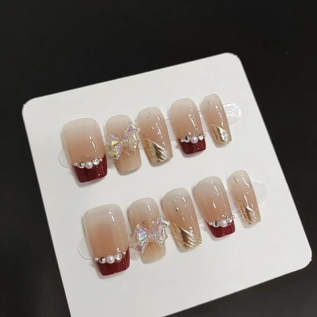 Krótkie tipsy z francuskim manicure, złotym brokatem i kokardką