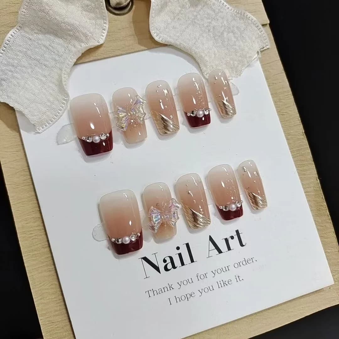 Krótkie paznokcie french tip ze złotym brokatem i kokardką