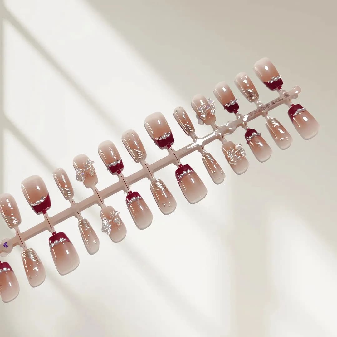 Krótkie tipsy z francuskim manicure, złotym brokatem i kokardką