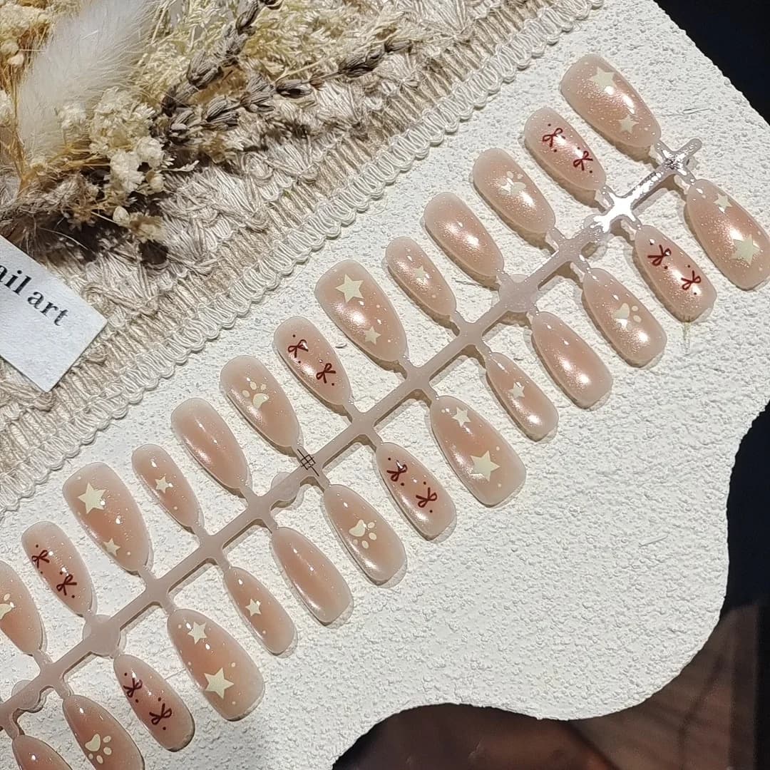 Nude różowe paznokcie typu cat eye z kokardką i gwiazdkami